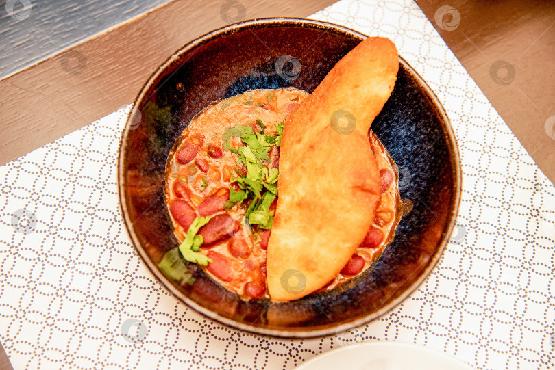 Скачать Традиционная грузинская овощная кухня - лобио из красной фасоли в черной тарелке фотосток Ozero