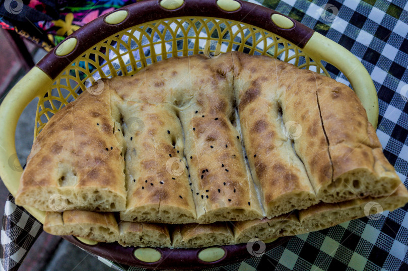 Скачать Свежеиспеченный азербайджанский хлеб-лепешка чурек в плетеной корзинке на столе фотосток Ozero