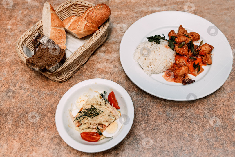 Скачать Обед-ужин с рисовым гарниром, кусочками курицы, салатом и хлебом в ресторане фотосток Ozero