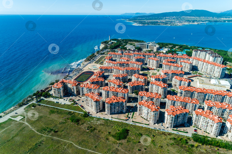 Скачать Панорама курорта Геленджик в солнечный день. На переднем плане многоэтажные здания. Маяк и вход в Геленджикскую бухту. Вид с высоты птичьего полета. фотосток Ozero
