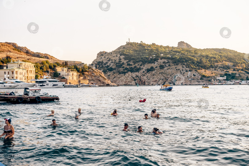 Скачать Балаклава, Крым, 21 июля 2020 года, Люди купаются в Черном море возле стоянки яхтенного катера фотосток Ozero