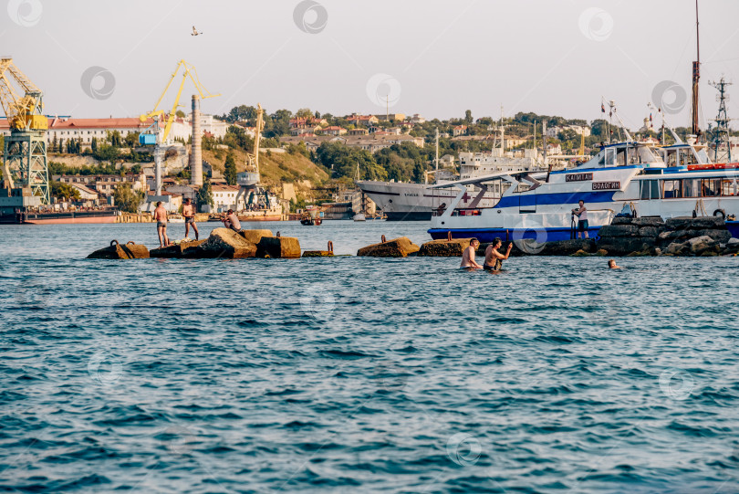 Скачать Балаклава, Крым, 21 июля 2020 года, Люди купаются в Черном море возле стоянки яхтенного катера фотосток Ozero