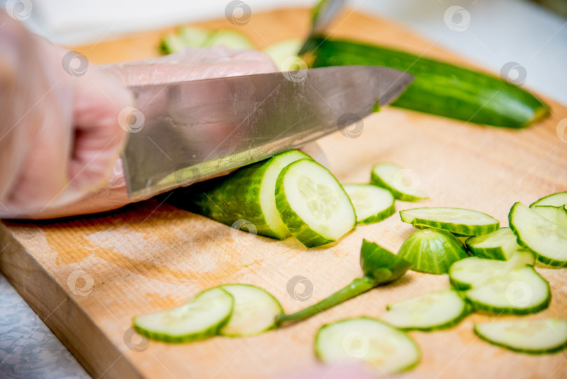 Скачать Шеф-повар кухни ресторана готовит овощной салат, крупным планом нарезает помидор и огурец фотосток Ozero