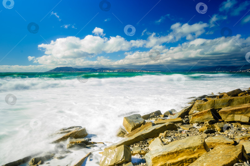 Скачать Курорт Кабардинка. Большие зеленые штормовые волны в белой пене. На заднем плане - порт Новороссийск и Кавказские горы. Большие камни на берегу. Фото с длительной выдержкой фотосток Ozero