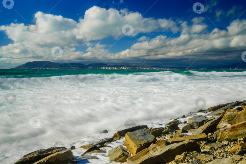 Скачать Курорт Кабардинка. Большие зеленые штормовые волны в белой пене. На заднем плане - порт Новороссийск и Кавказские горы. Большие камни на берегу. Фото с длительной выдержкой фотосток Ozero