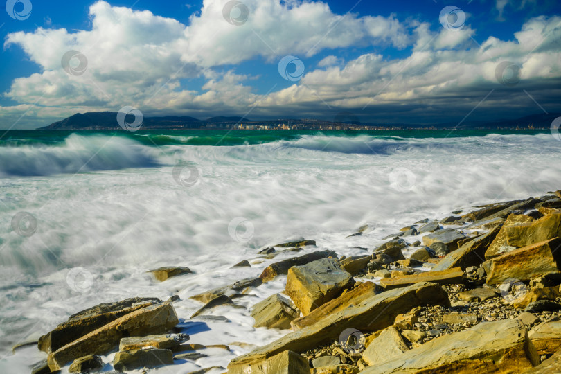 Скачать Курорт Кабардинка. Большие зеленые штормовые волны в белой пене. На заднем плане - порт Новороссийск и Кавказские горы. Большие камни на берегу. Фото с длительной выдержкой фотосток Ozero