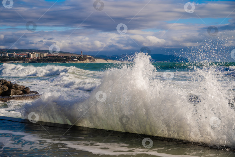 Скачать Курорт Геленджик. Большие зеленые штормовые волны накатывают на фоне Геленджикского маяка. Маяк стоит на высоком утесе. Брызги на переднем плане фотосток Ozero
