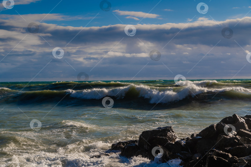 Скачать Курорт Геленджик. Большие зеленые штормовые волны в белой пене накатываются на каменистый пляж Геленджика. Большие камни на берегу. Брызги и пена от волн фотосток Ozero