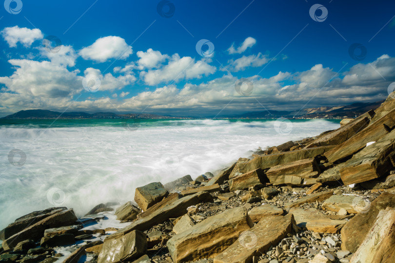 Скачать Курорт Кабардинка. Большие зеленые штормовые волны в белой пене. На заднем плане - порт Новороссийск и Кавказские горы. Большие камни на берегу. Фото с длительной выдержкой фотосток Ozero