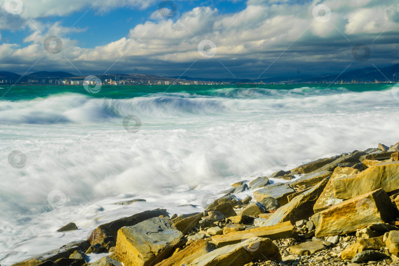 Скачать Курорт Кабардинка. Большие зеленые штормовые волны в белой пене. На заднем плане - порт Новороссийск и Кавказские горы. Большие камни на берегу. Фото с длительной выдержкой фотосток Ozero