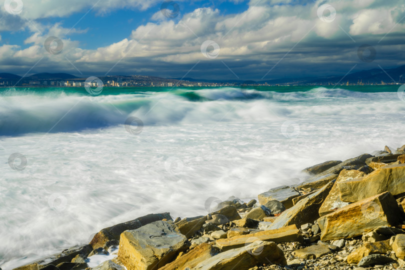 Скачать Курорт Кабардинка. Большие зеленые штормовые волны в белой пене. На заднем плане - порт Новороссийск и Кавказские горы. Большие камни на берегу. Фото с длительной выдержкой фотосток Ozero
