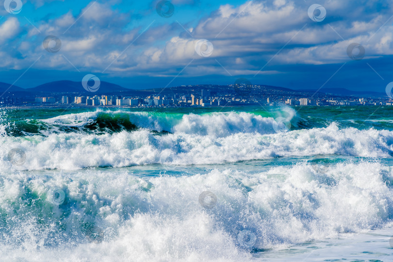 Скачать Курорт Кабардинка. Черное море. Большие штормовые волны изумрудного цвета накатывают на берег. Множество брызг и пены. Порт Новороссийск и Кавказские горы на горизонте фотосток Ozero