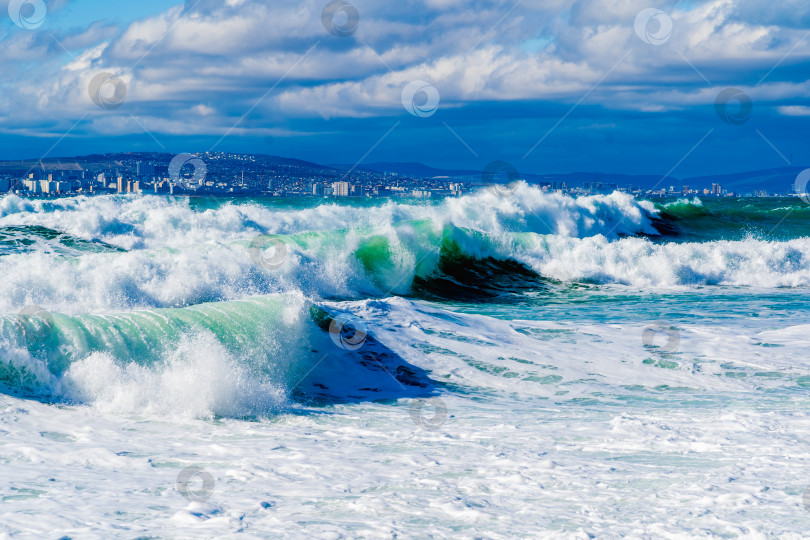 Скачать Курорт Кабардинка. Черное море. Большие штормовые волны изумрудного цвета накатывают на берег. Множество брызг и пены. Порт Новороссийск и Кавказские горы на горизонте фотосток Ozero