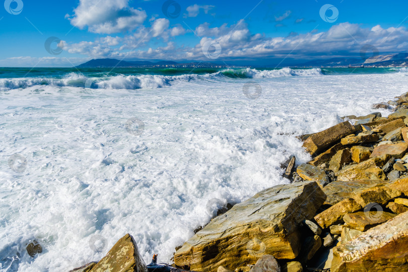 Скачать Курорт Кабардинка. Большие зеленые штормовые волны в белой пене накатываются на каменистый пляж Кабардинки. На заднем плане - порт Новороссийск и Кавказские горы. фотосток Ozero