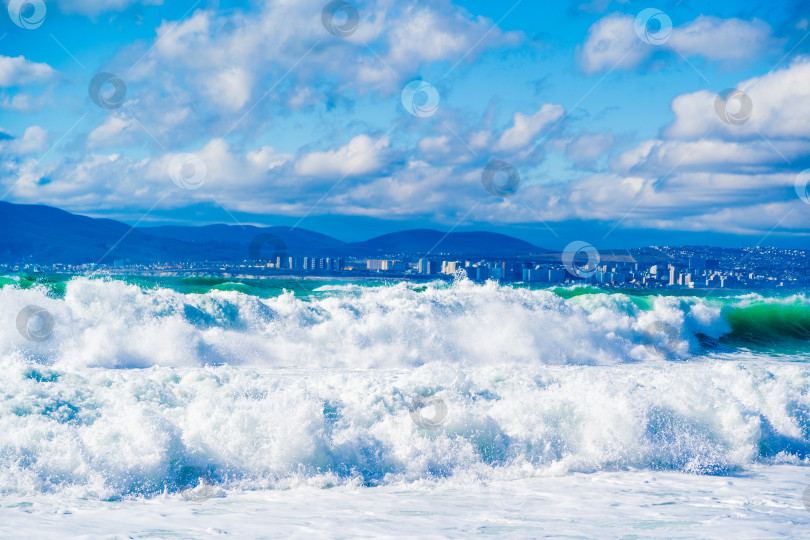 Скачать Курорт Кабардинка. Большие зеленые штормовые волны в белой пене накатываются на каменистый пляж Кабардинки. На заднем плане - порт Новороссийск и Кавказские горы. фотосток Ozero