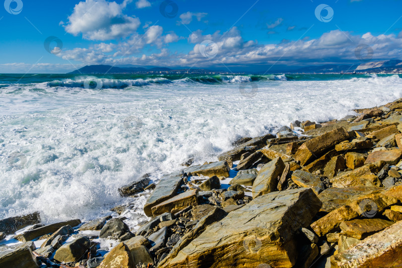 Скачать Курорт Кабардинка. Большие зеленые штормовые волны в белой пене накатываются на каменистый пляж Кабардинки. На заднем плане - порт Новороссийск и Кавказские горы. Большие камни на берегу фотосток Ozero
