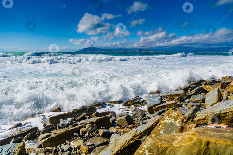 Скачать Курорт Кабардинка. Большие зеленые штормовые волны в белой пене накатываются на каменистый пляж Кабардинки. На заднем плане - порт Новороссийск и Кавказские горы. Большие камни на берегу фотосток Ozero