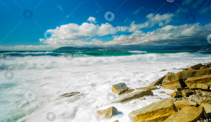 Скачать Курорт Кабардинка. Большие зеленые штормовые волны в белой пене. На заднем плане - порт Новороссийск и Кавказские горы. Большие камни на берегу. Фото с длительной выдержкой фотосток Ozero