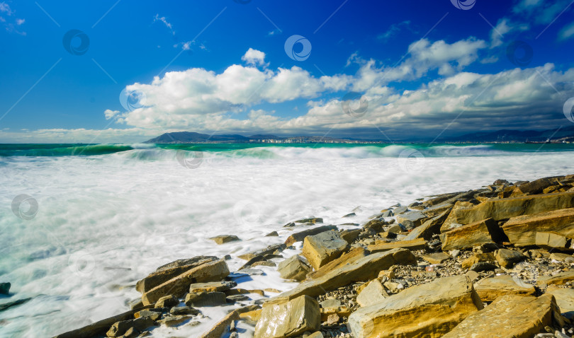 Скачать Курорт Кабардинка. Большие зеленые штормовые волны в белой пене. На заднем плане - порт Новороссийск и Кавказские горы. Большие камни на берегу. Фото с длительной выдержкой фотосток Ozero