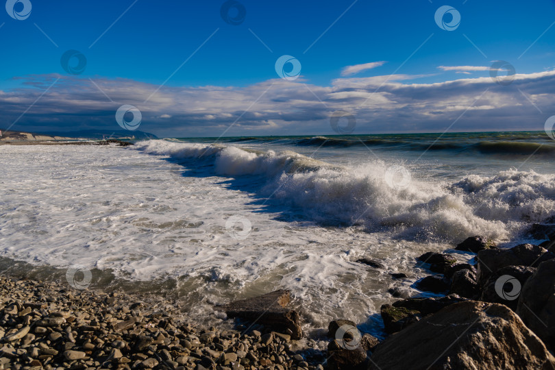 Скачать Курорт Геленджик. Большие зеленые штормовые волны в белой пене накатываются на каменистый пляж Геленджика. Большие камни на берегу. Брызги и пена от волн фотосток Ozero