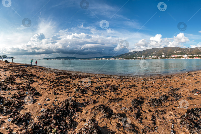Скачать Курорт Геленджик. Пляж со скалистой береговой линией и облачным небом фотосток Ozero