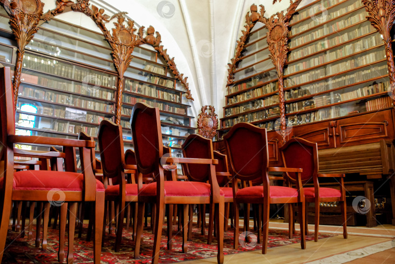 Скачать Элегантная антикварная библиотека с богато украшенными полками и красными бархатными креслами фотосток Ozero