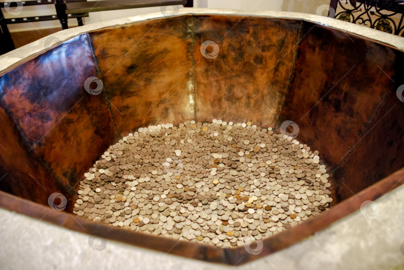 Скачать Монеты скапливаются в большом металлическом контейнере в помещении фотосток Ozero