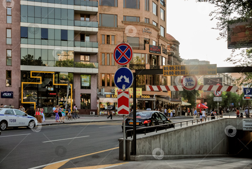 Скачать Городская улица с дорожными знаками и пешеходами в вечернем освещении фотосток Ozero