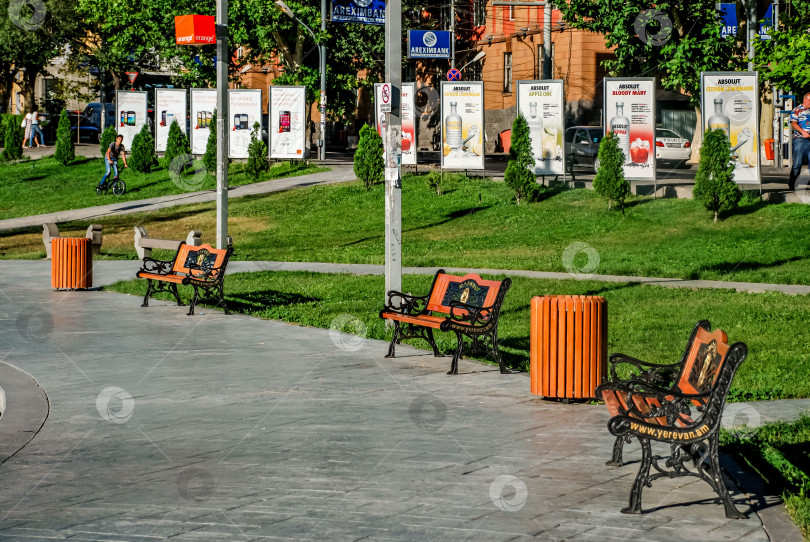 Скачать Открытый парк с оранжевыми скамейками и плакатами в городских условиях фотосток Ozero