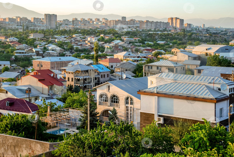 Скачать Городской пейзаж с разнообразной архитектурой и зеленью на фоне современного горизонта на рассвете фотосток Ozero