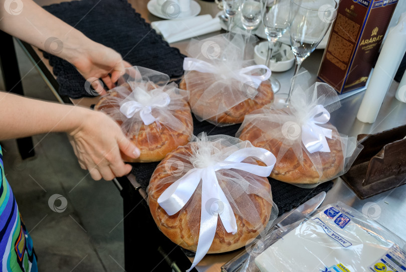 Скачать Кавказская женщина готовит на столе завернутые в белую ленту буханки хлеба фотосток Ozero