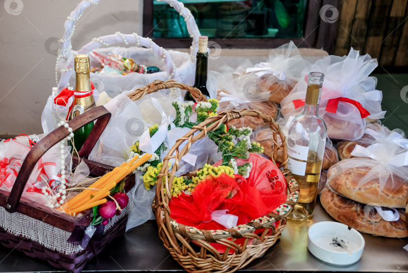 Скачать На столе выставлены разнообразные подарочные корзины с бутылками вина и булочками фотосток Ozero