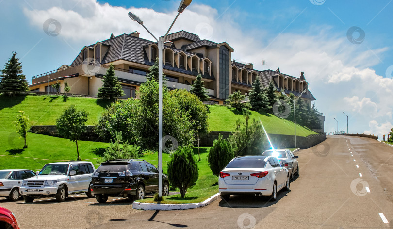 Скачать Роскошная резиденция на склоне холма с припаркованными автомобилями под ясным небом фотосток Ozero