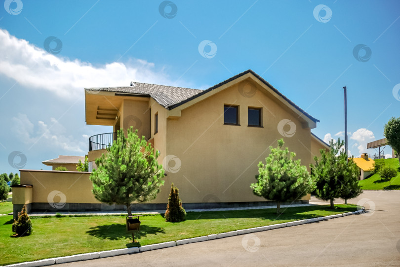 Скачать Современный загородный дом с лужайкой и соснами под ясным голубым небом фотосток Ozero