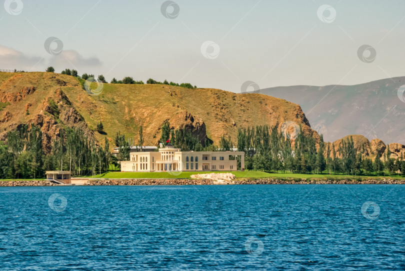 Скачать Величественное здание на берегу озера на фоне гор под ясным небом фотосток Ozero