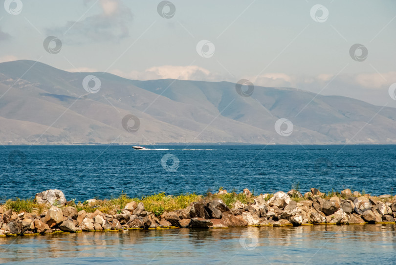 Скачать Живописный вид на озеро со скоростным катером и горами на фоне фотосток Ozero