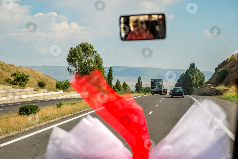 Скачать Живописный вид на шоссе с украшениями свадебного автомобиля в зеркальном отражении фотосток Ozero