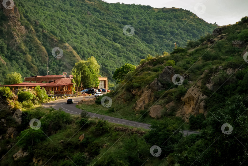 Скачать Безмятежная горная дорога с автомобилями и домиком среди пышной зелени фотосток Ozero