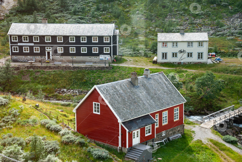 Скачать Живописные красные и белые дома в скандинавской сельской местности с пышной зеленью фотосток Ozero