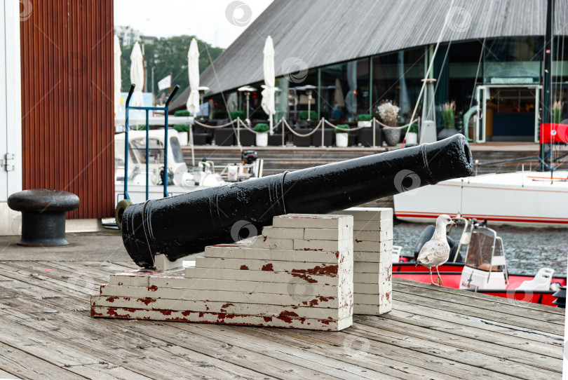 Скачать Историческая черная пушка на выветренной платформе у пристани для яхт с лодками фотосток Ozero