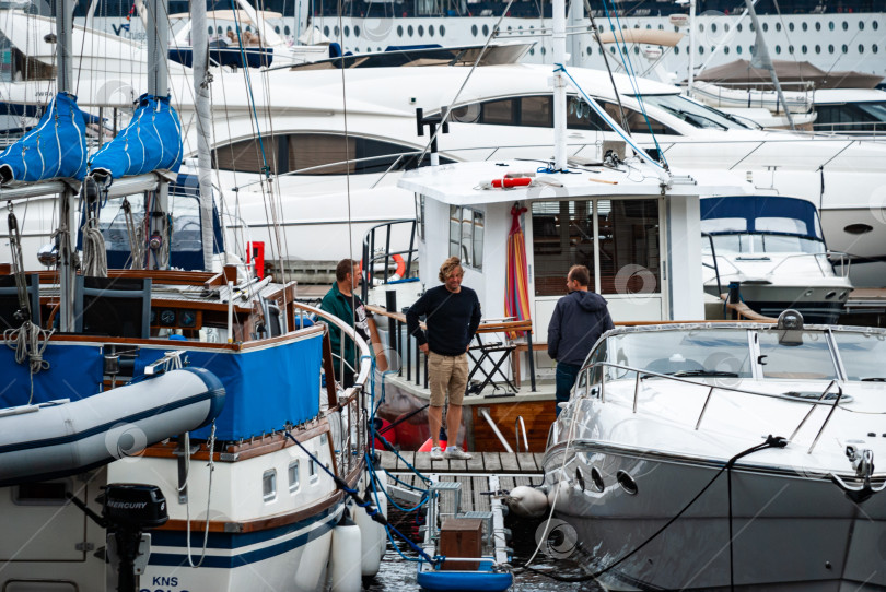 Скачать Мужчины беседуют на пристани для яхт на фоне роскошных яхт фотосток Ozero