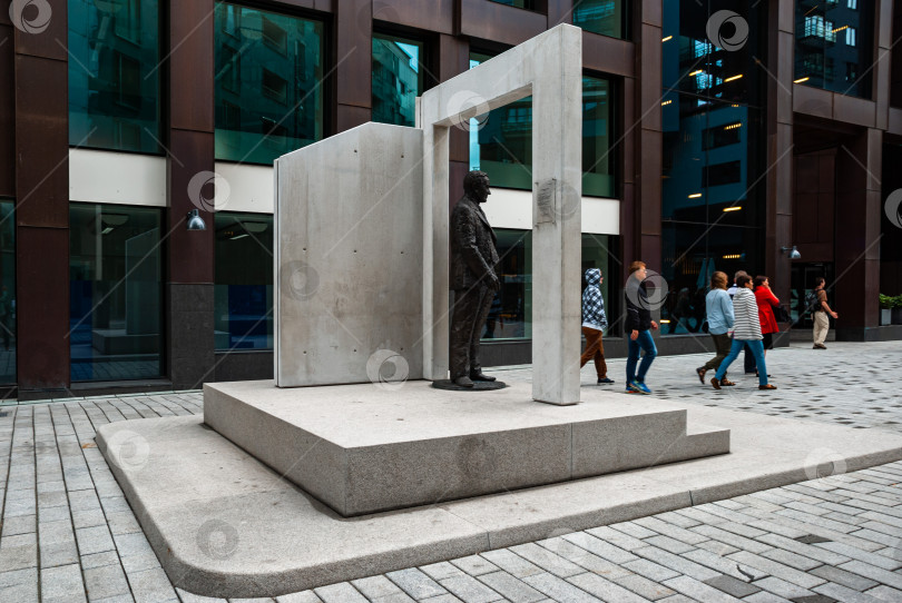Скачать Современная городская скульптура белого мужчины на фоне оживленного городского пейзажа фотосток Ozero