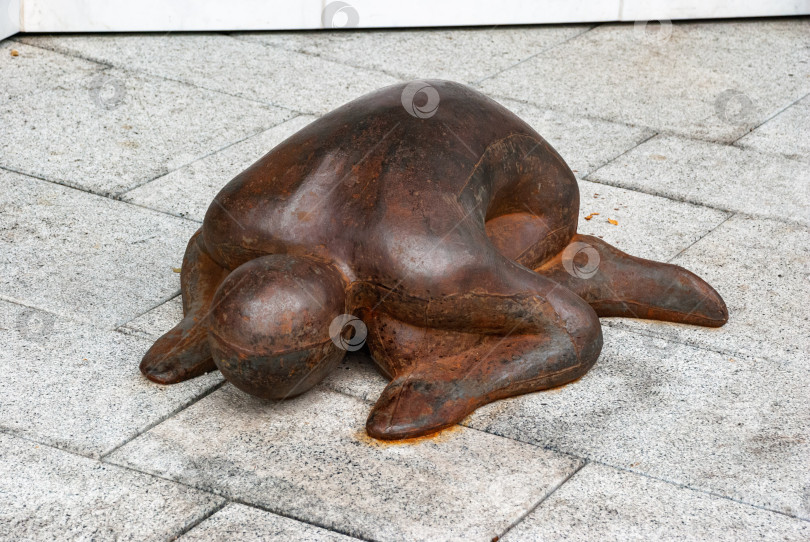 Скачать Бронзовая скульптура человеческой фигуры в коленопреклоненной позе на каменном полу фотосток Ozero