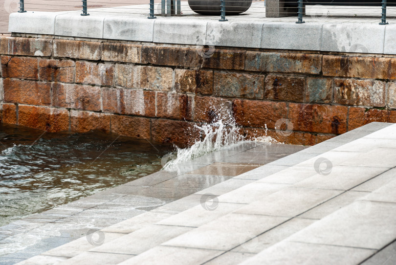 Скачать Плеск волн о каменный пирс с металлическими перилами в пасмурный день фотосток Ozero