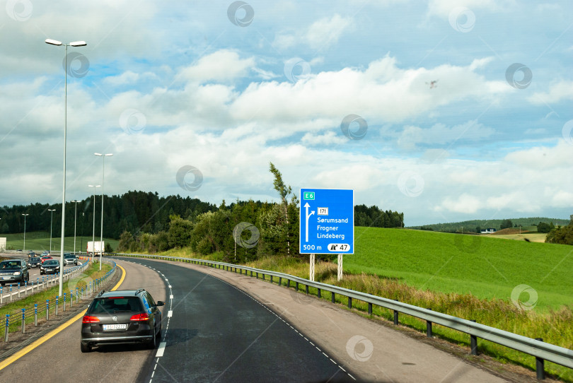 Скачать Живописное шоссе с дорожным движением и дорожным знаком в сельской местности фотосток Ozero