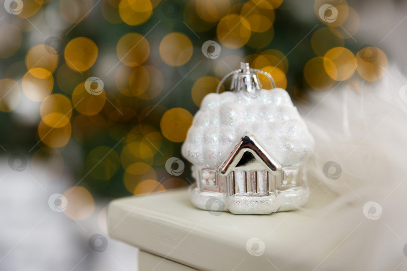 Скачать Рождественский стеклянный игрушечный домик на фоне желтых огоньков гирлянд фотосток Ozero
