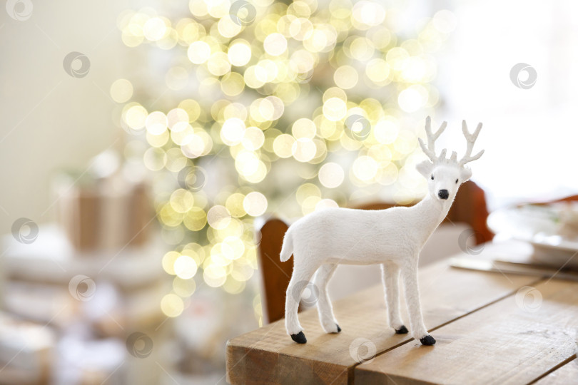 Скачать Игрушка или фигурка оленя на фоне размытой комнаты и рождественской елки фотосток Ozero