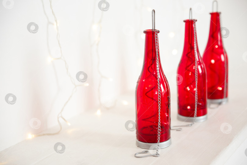 Скачать красные бутылки с гирляндой внутри стоят на белом фоне фотосток Ozero