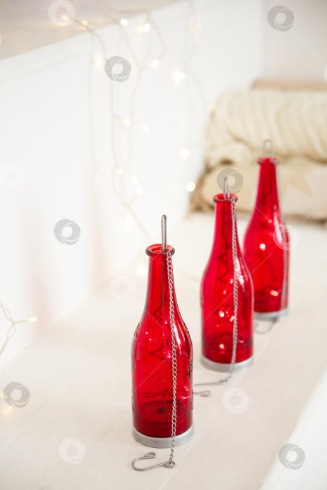 Скачать красные бутылки с гирляндой внутри стоят на белом фоне фотосток Ozero