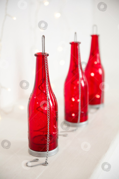 Скачать красные бутылки с гирляндой внутри стоят на белом фоне фотосток Ozero
